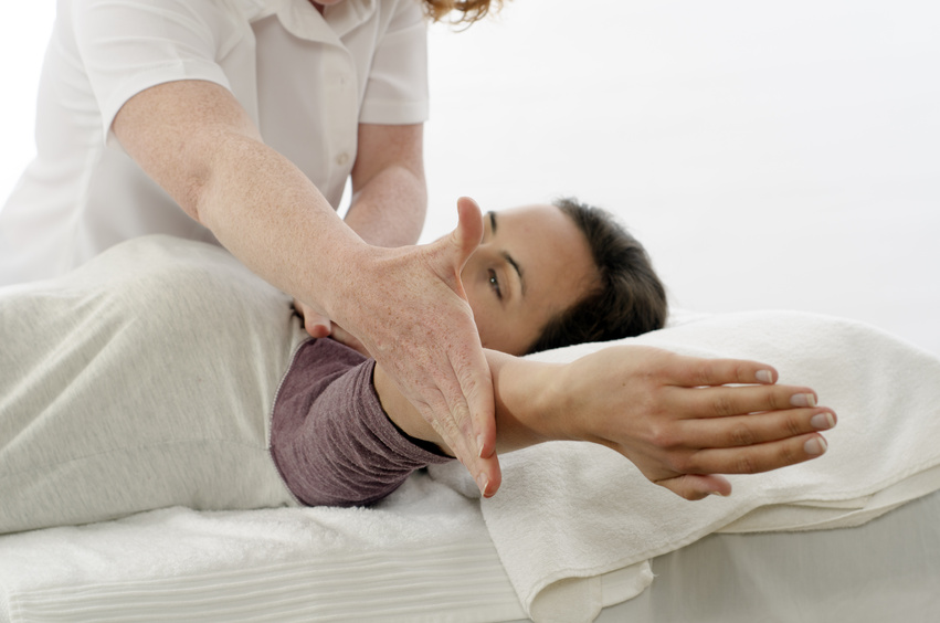 Therapeut hält den angehobenen Arm einer liegenden Person